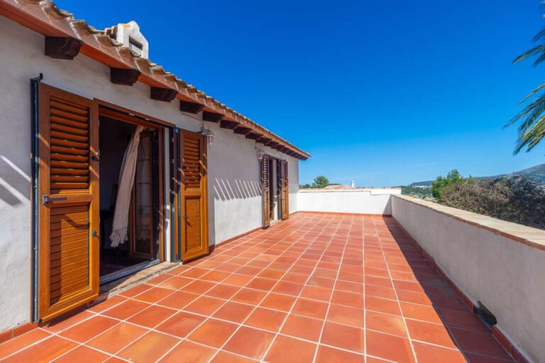 Sunny upper terrace at a traditional Spanish finca near Moraira with wooden shutters, tiled flooring, white walls and open countryside views