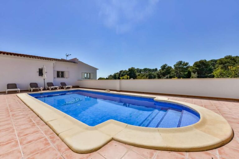Swimming pool at a charming Benissa Coast villa with tiled terrace, sun loungers, white garden walls and peaceful residential surroundings