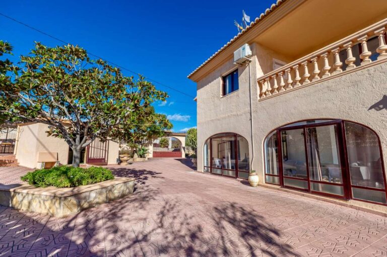 Terrace area with garden tree and exterior view of a spacious villa with guest apartments in Calpe.
