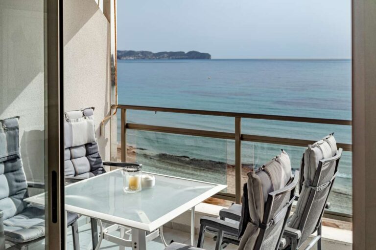 Terrace at a beachfront apartment by La Fossa Beach in Calpe with outdoor table, chairs and Mediterranean Sea views