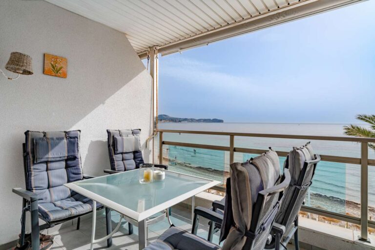 Terrace dining area at a beachfront apartment by La Fossa Beach in Calpe with outdoor table, chairs and Mediterranean Sea views
