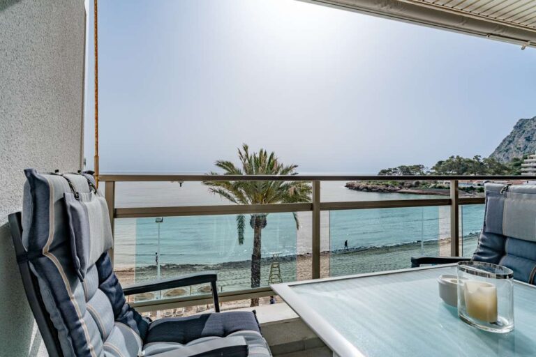 Terrace seating at a beachfront apartment by La Fossa Beach in Calpe with outdoor chairs, table, palm tree views and Mediterranean Sea beyond