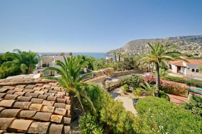 Terrace views across Calpe with palm trees and mountain scenery from a second line Mediterranean villa near Puerto Blanco.