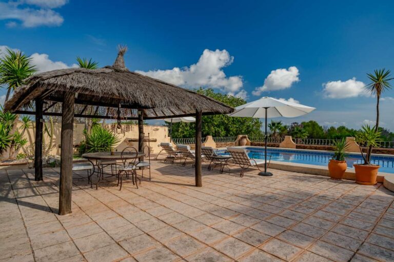 Thatched pavilion beside the private pool at a historic finca in Benissa with outdoor seating, terrace space and Mediterranean planting