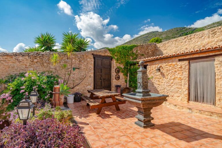 Traditional courtyard at a historic finca in Benissa with stone walls, fountain, outdoor seating and Mediterranean planting