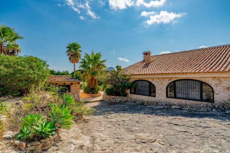 Traditional exterior of a historic finca in Benissa with stone walls, arched windows, tiled roof and Mediterranean planting