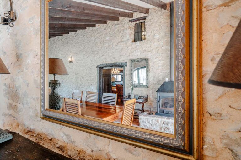 Traditional interior detail inside a historic Benissa finca with exposed stone walls, wooden beams, mirror and rustic Mediterranean character