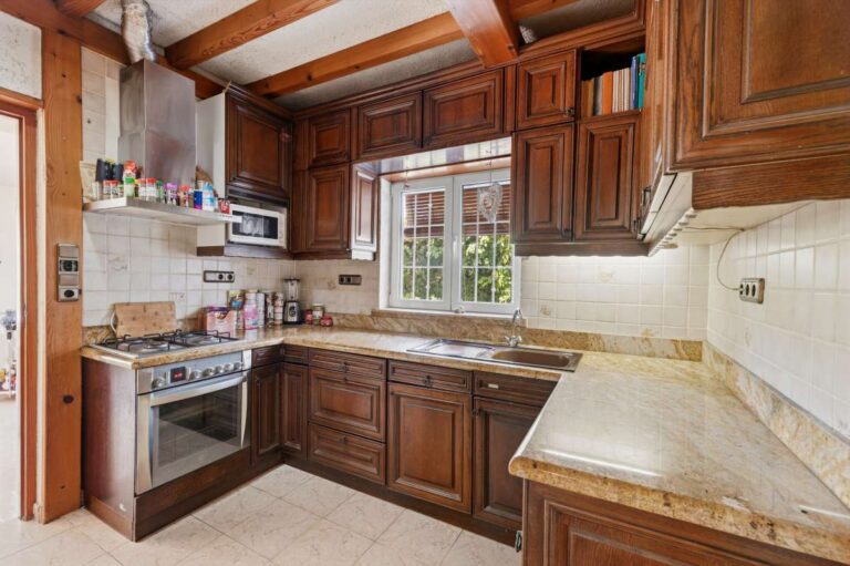 Traditional kitchen inside a Mediterranean villa in Benissa Costa near Cala Baladrar with wooden cabinetry, tiled worktops and natural light