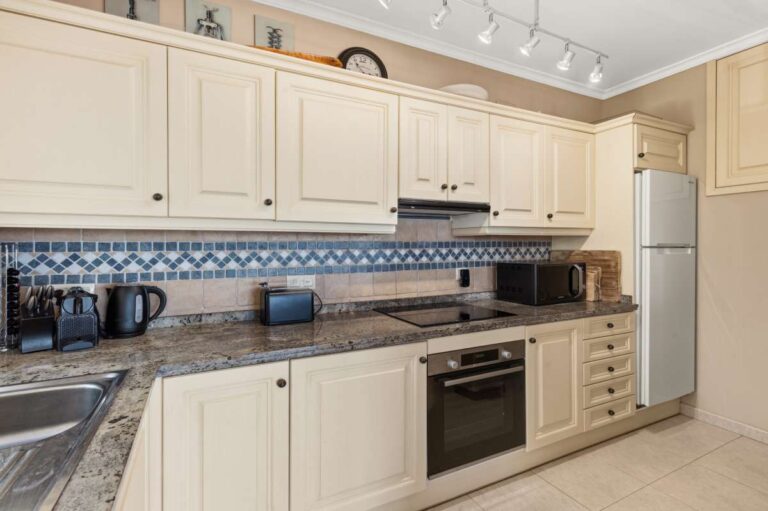 Traditional kitchen inside an elegant Mediterranean villa in Altea Hills with cream cabinetry, granite worktops, tiled splashback and integrated appliances