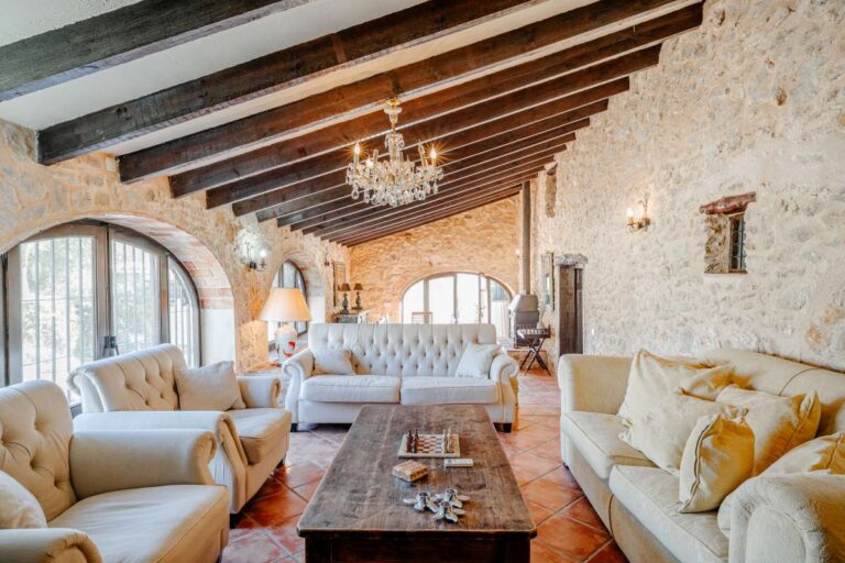 Traditional living room inside a historic finca in Benissa with stone walls, wooden beams, chandelier and classic Mediterranean character