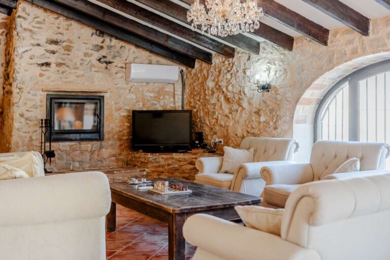 Traditional lounge inside a historic luxury finca in Benissa with stone walls, wooden beams, chandelier and classic seating area