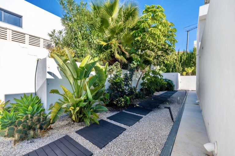 Tropical garden pathway with privacy planting and gravel landscaping at a modern oasis villa in Calpe.