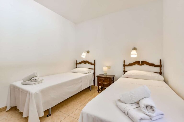Twin bedroom inside a charming Benissa Coast villa with two single beds, bedside lighting, towels and simple Mediterranean interior