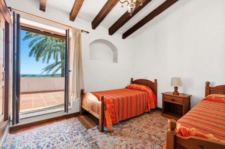 Twin bedroom inside a traditional Spanish finca near Moraira with two single beds, beamed ceiling, terrace access and rustic Mediterranean details