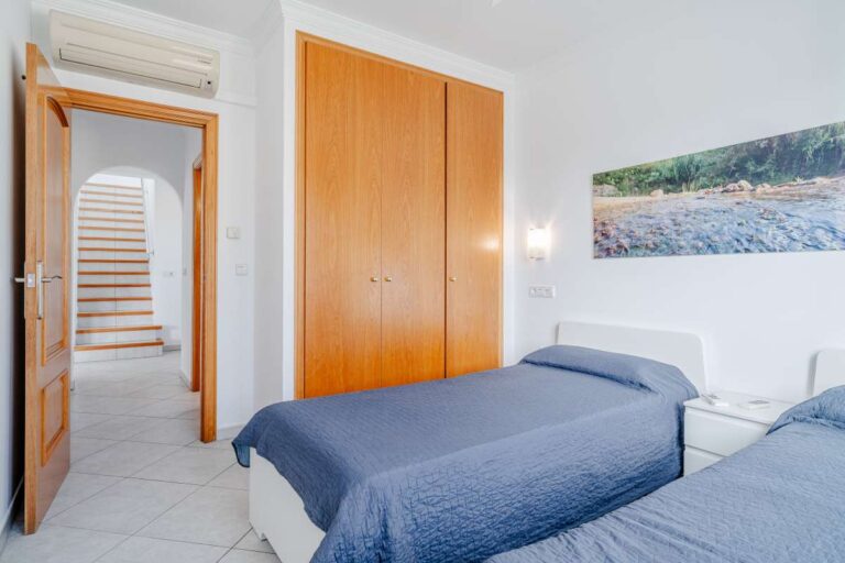 Twin bedroom inside a villa in Calpe with built-in wardrobe, tiled floor and access to the hallway