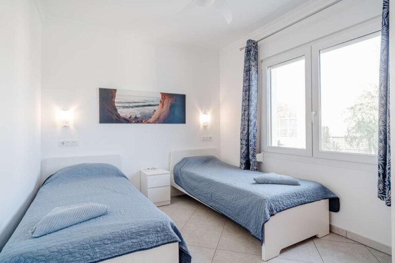 Twin bedroom inside a villa in Calpe with large window, tiled floor and natural light