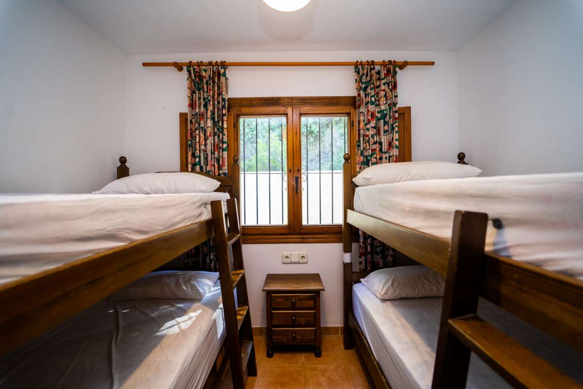Twin bedroom with bunk beds, traditional wooden furniture and natural light inside a Mediterranean villa in Cometa III, Calpe.