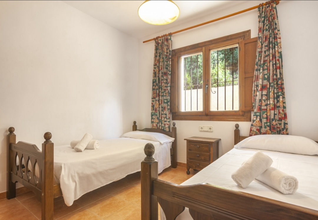 Twin bedroom with traditional furniture and natural light inside a Mediterranean villa with mountain views in Calpe.
