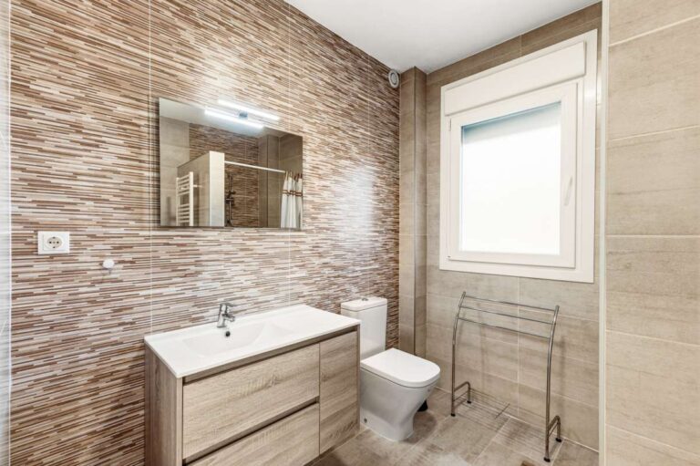 Upper floor bathroom with vanity, window and modern tile detailing inside a contemporary villa in Calpe.