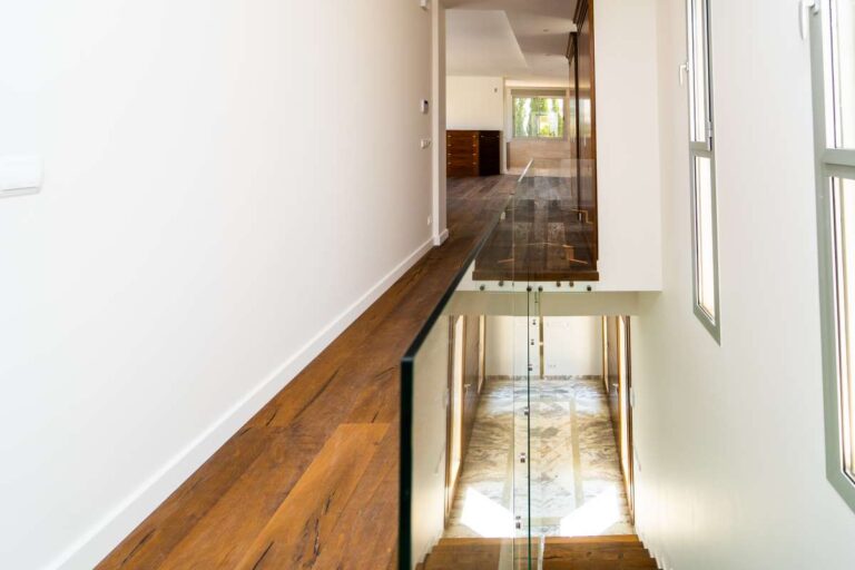 Upper hallway inside a luxury villa in Calpe with wood flooring, glass balustrade and views towards the main entrance level