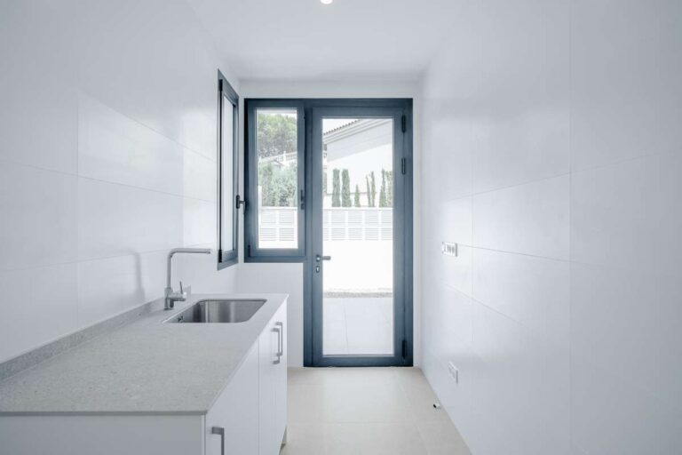 Utility room inside a modern villa in La Calalga, Calpe with sink, storage units and exterior access door