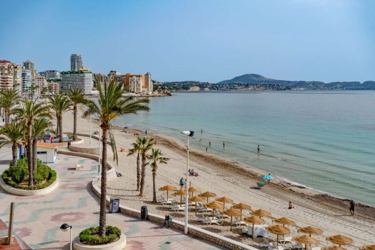 Views from a beachfront apartment by La Fossa Beach in Calpe showing the promenade, sandy beach, palm trees and Mediterranean Sea