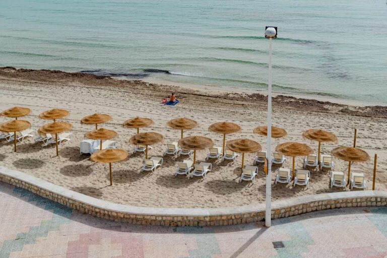 Views from a beachfront apartment by La Fossa Beach in Calpe showing the promenade, sunbed area, sandy beach and Mediterranean Sea