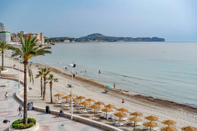 Views from a beachfront apartment by La Fossa Beach in Calpe showing the sandy beach, promenade, Mediterranean Sea and distant coastline