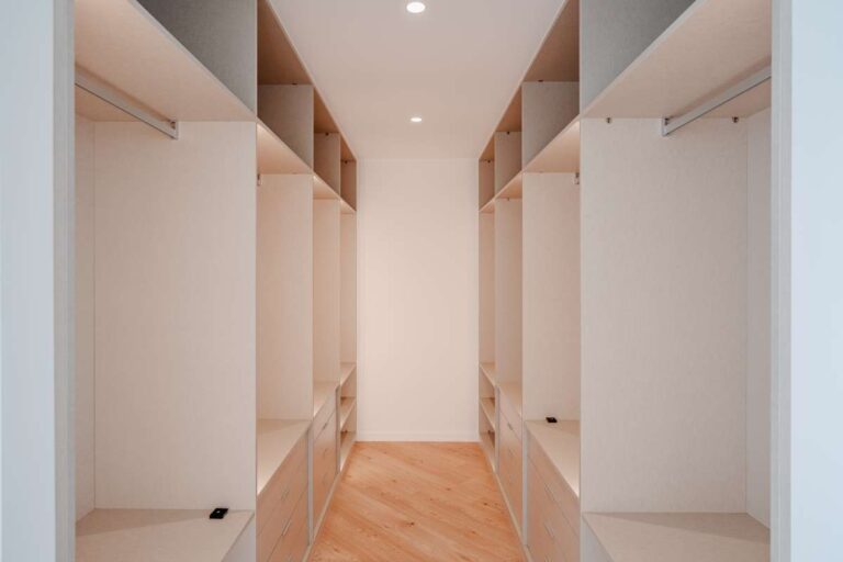 Walk-in dressing room inside a modern second-line sea villa in La Calalga, Calpe with fitted open wardrobes and wood flooring