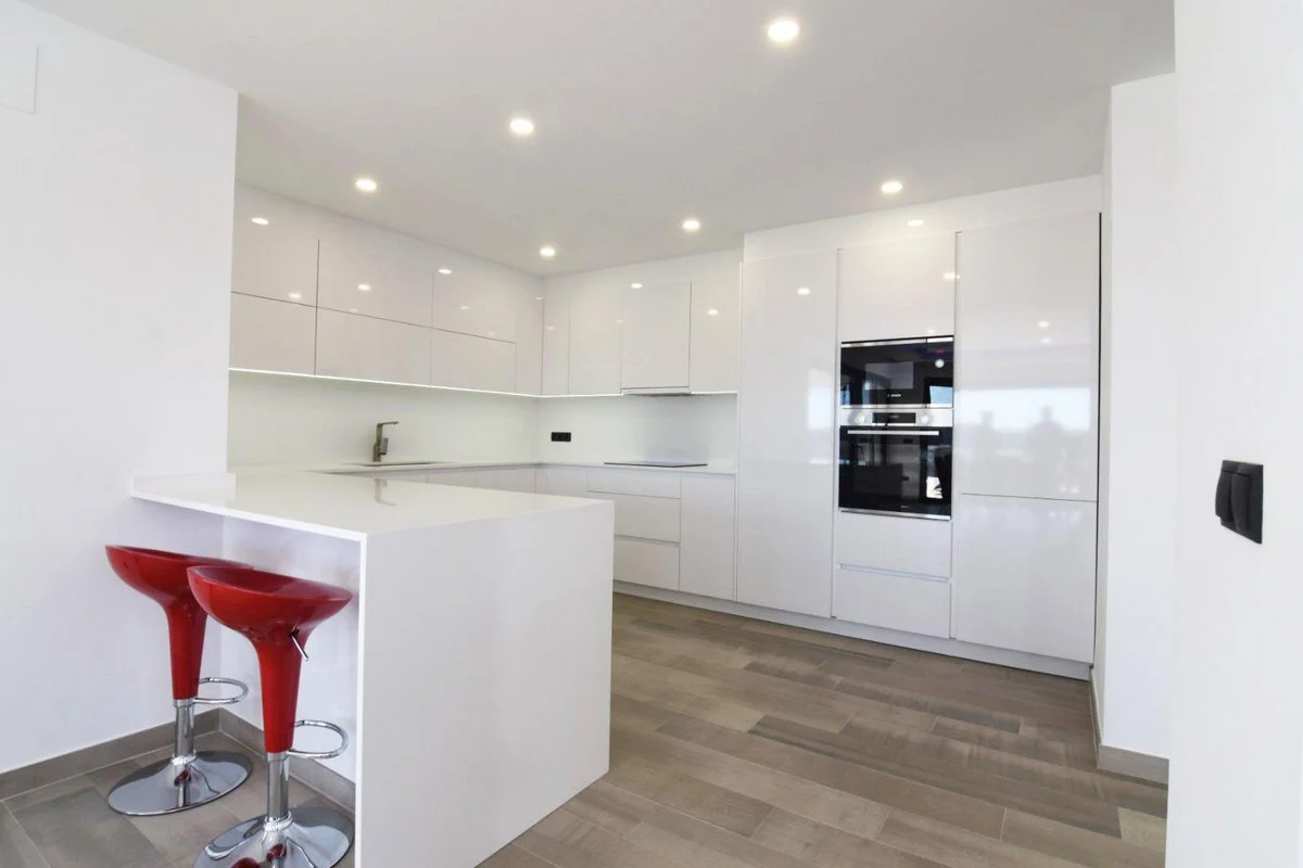 White open-plan kitchen with breakfast bar in modern villa in Calpe