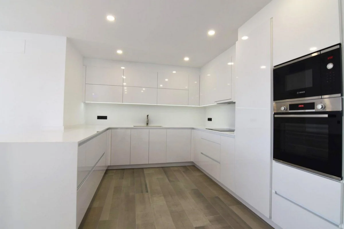 White open-plan kitchen with built-in appliances in modern villa in Carrió, Calpe