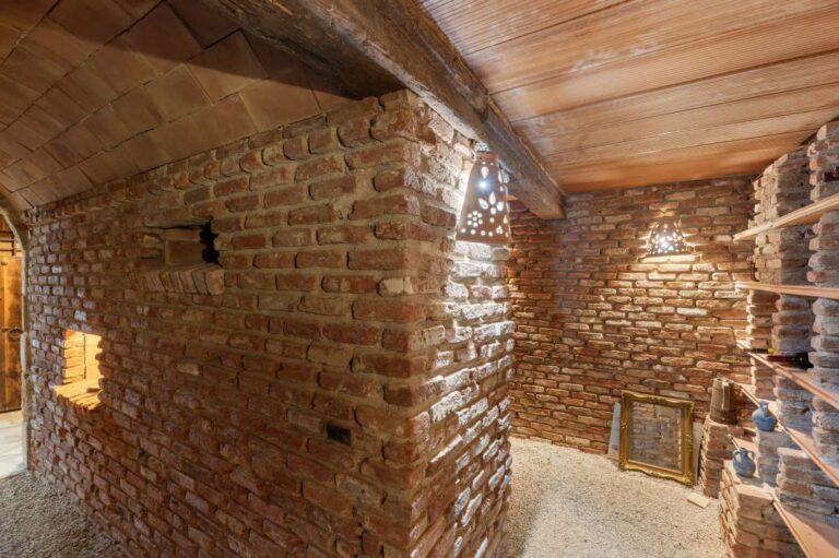 Wine cellar inside a finca-style villa in Benissa Costa with exposed brick walls, wooden ceiling, storage shelving and rustic character