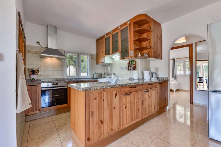 Wooden kitchen inside a charming Benissa Coast villa with breakfast bar, integrated appliances, granite worktops and open-plan layout
