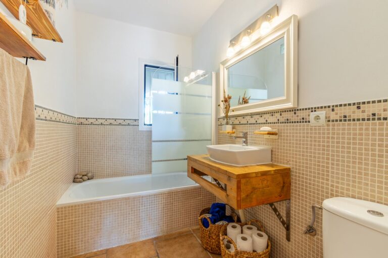 Bathroom inside a Mediterranean villa near Cala Baladrar in Benissa Costa with bath, vanity unit, mirror, toilet and tiled walls