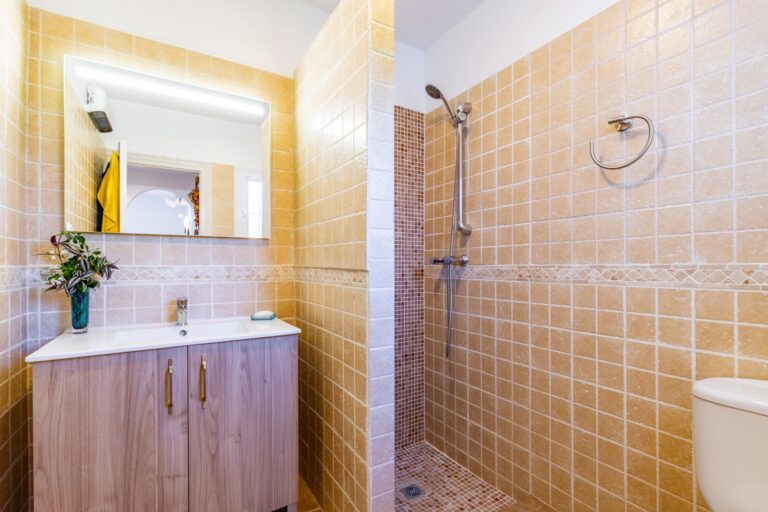 Bathroom inside a Mediterranean villa near Cala Baladrar in Benissa Costa with walk-in shower, vanity unit, mirror and warm tiled finish