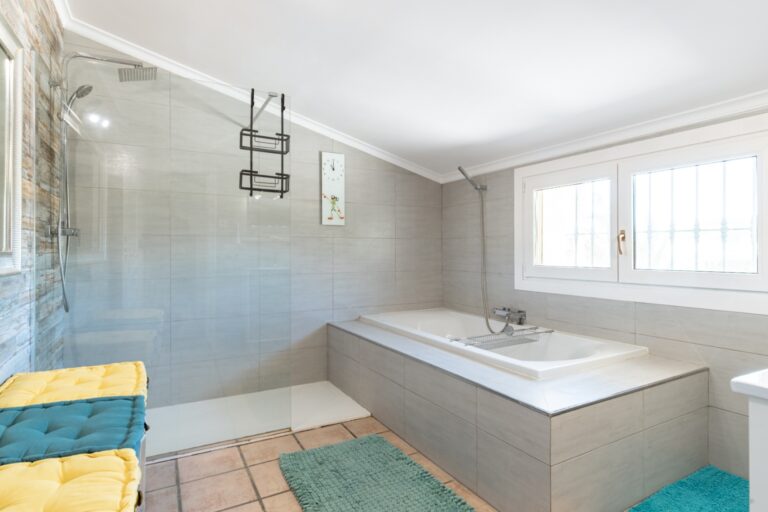 Bathroom inside a renovated finca near Teulada and Moraira with bathtub, shower area, towel rail, bright window and tiled flooring