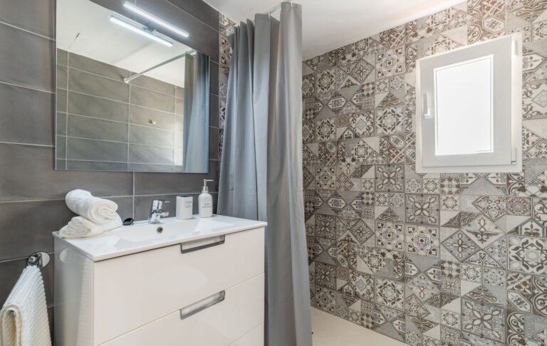 Bathroom inside a renovated Mediterranean villa near Cala Baladrar in Benissa Costa with vanity unit, mirror, walk-in shower and patterned tile detail