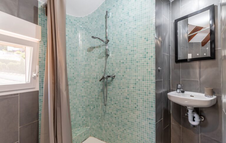 Bathroom inside a renovated Mediterranean villa near Cala Baladrar in Benissa Costa with walk-in shower, mosaic tile detail, sink and bright window