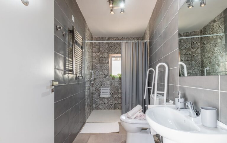 Bathroom inside a renovated villa near Cala Baladrar in Benissa Costa with walk-in shower, grey wall tiles, sink, toilet and modern fittings