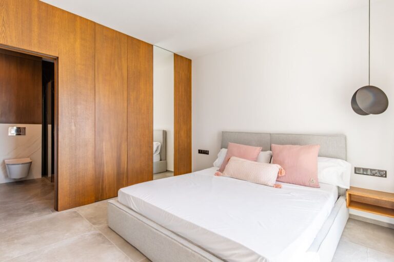 Bedroom inside a luxury smart home villa near Moraira with en-suite access, fitted wooden wardrobes, white bed and premium contemporary finish