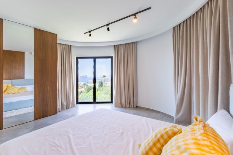 Bedroom inside a luxury smart home villa near Moraira with garden views, large window, fitted wooden wardrobes, neutral finishes and natural light