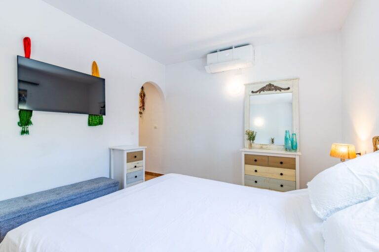 Bedroom inside a Mediterranean villa near Cala Baladrar in Benissa Costa with double bed, air conditioning, wall-mounted TV and bright neutral finish