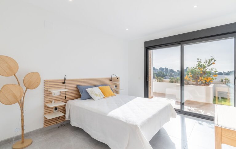 Bedroom inside a modern villa in Pla del Mar, Moraira with double bed, terrace access, large sliding doors and bright neutral finish
