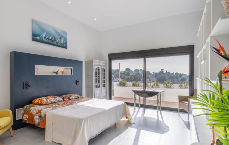 Bedroom inside a modern villa in Pla del Mar, Moraira with large window, fitted shelving, bright interior and views across the surrounding area