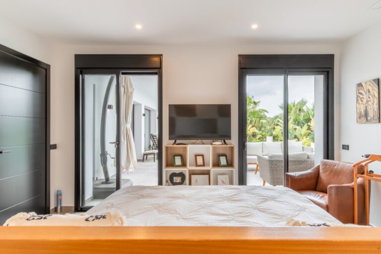 Bedroom inside a modern villa in Solpark, Moraira with outdoor access, double bed, TV area, large sliding doors and bright modern interior