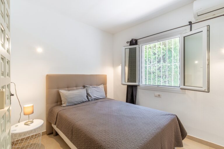Bedroom inside a renovated Mediterranean villa in Moraira with double bed, air conditioning, bright window and neutral interior finish