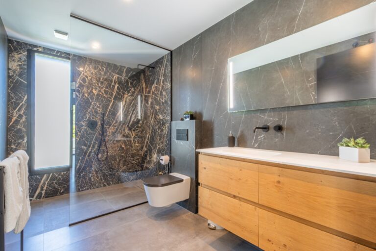 Contemporary bathroom inside a modern villa in Solpark, Moraira with double vanity, dark marble-effect tiles, wooden cabinetry and premium finish
