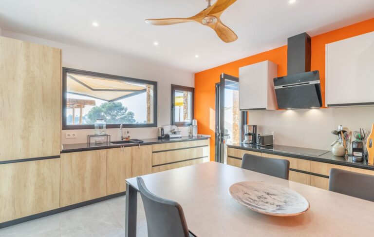 Contemporary kitchen inside a modern villa in Pla del Mar, Moraira with island, fitted cabinetry, large window and bright modern interior