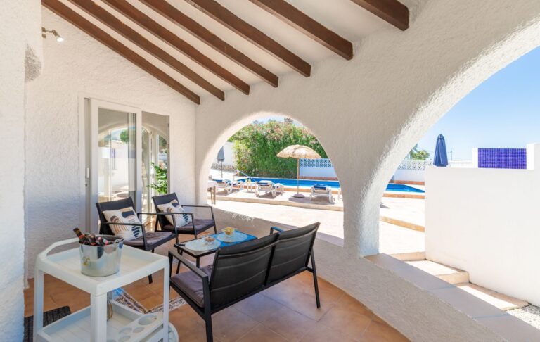 Covered outdoor lounge at a renovated Mediterranean villa near Cala Baladrar in Benissa Costa with arched naya, pool views and shaded seating area