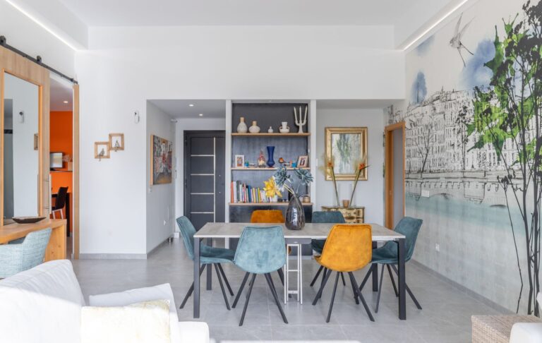 Dining area inside a modern villa in Pla del Mar, Moraira with colourful chairs, open-plan layout, feature wall and contemporary interior styling